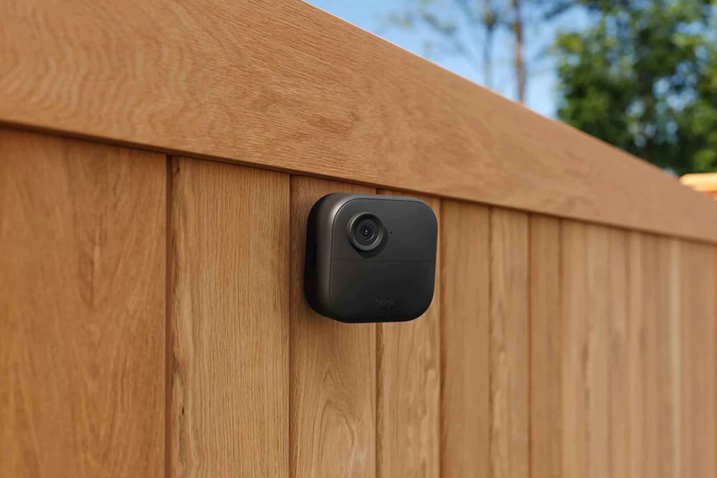 Camera an ninh Blink Outdoor 4 được gắn trên hàng rào, minh họa khả năng giám sát ngoài trời hiệu quả.