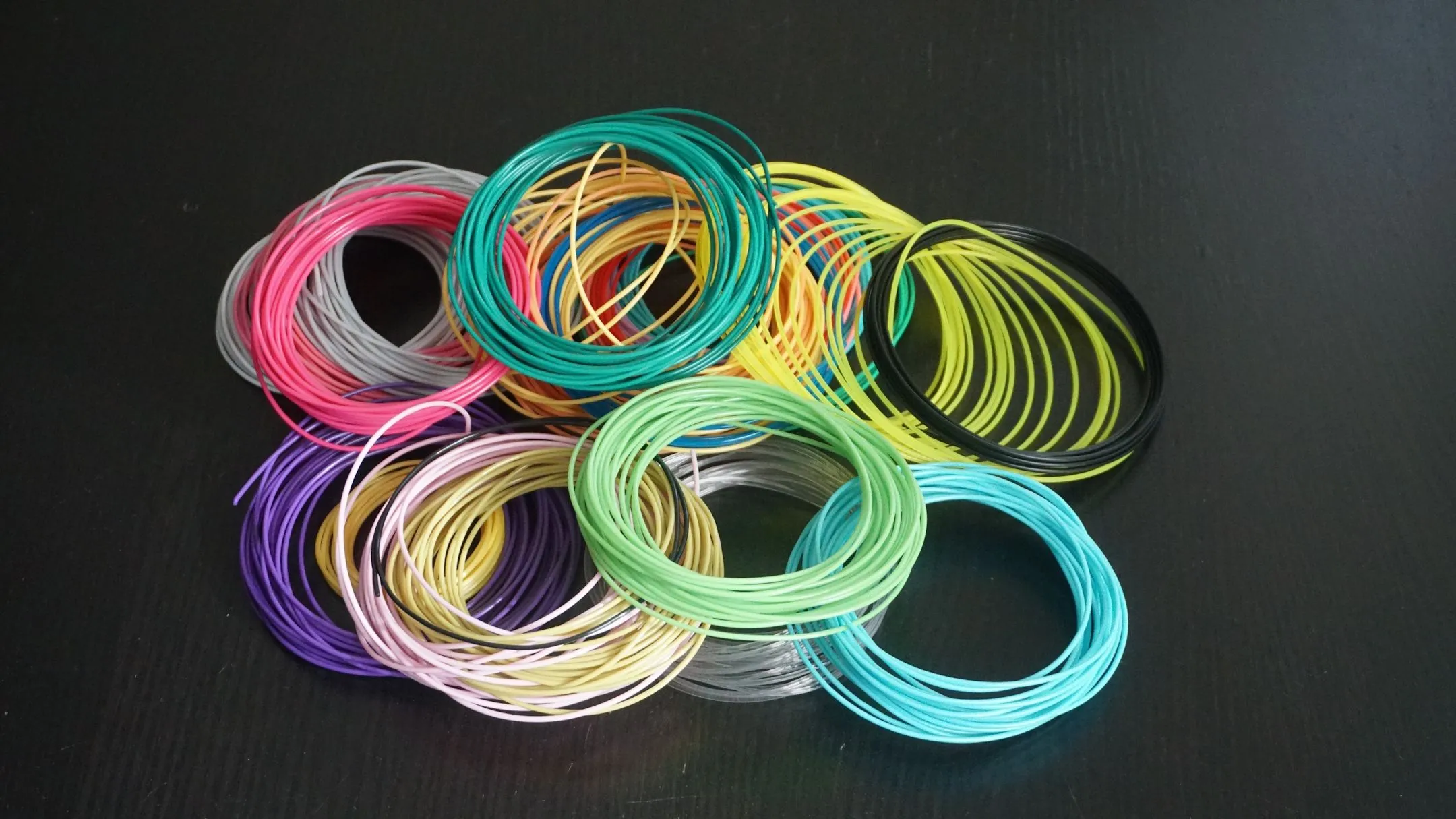 Cuộn vật liệu in 3D (filament) với nhiều màu sắc khác nhau, biểu trưng cho sự đa dạng và tầm quan trọng của việc lựa chọn loại vật liệu phù hợp cho từng dự án in 3D.