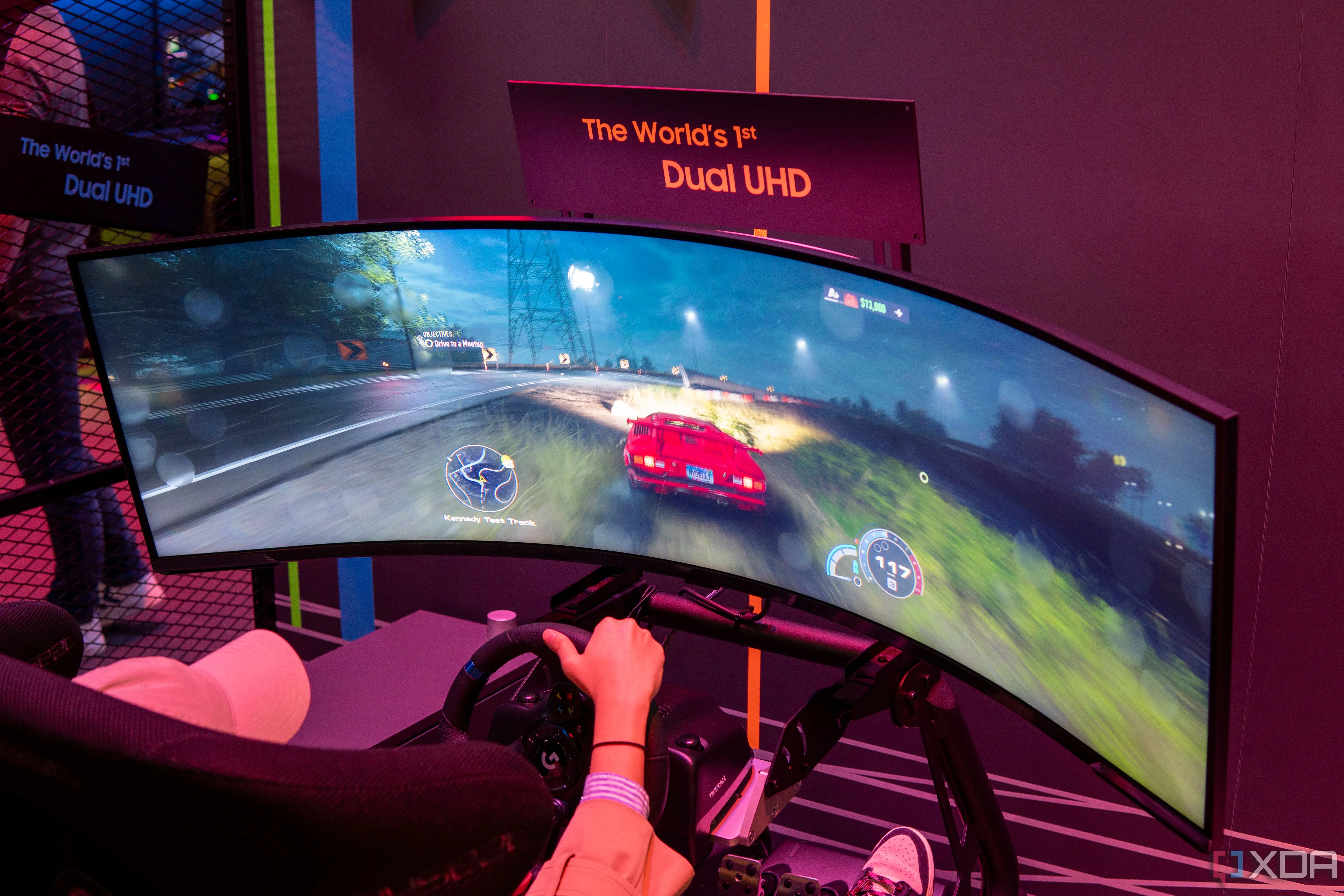 Màn hình Samsung Odyssey Neo G9 57 inch đang hiển thị một trò chơi đua xe được điều khiển bằng vô lăng, thể hiện kích thước ấn tượng và trải nghiệm nhập vai