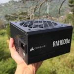 Một người đang cầm bộ nguồn Corsair RM1000e màu đen.
