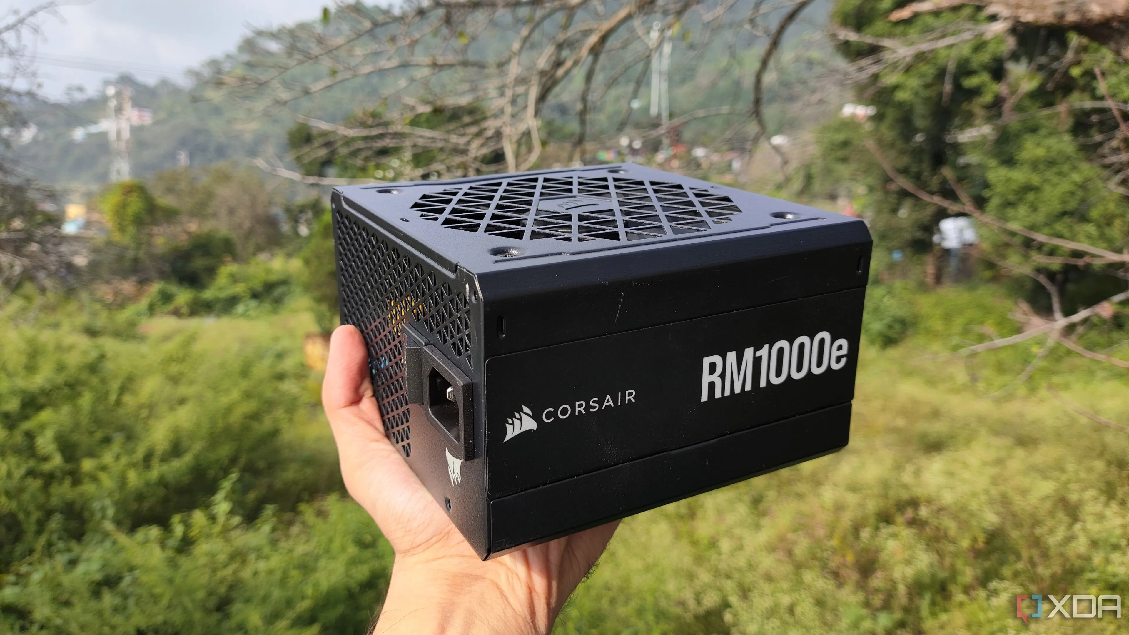 Một người đang cầm bộ nguồn Corsair RM1000e màu đen.
