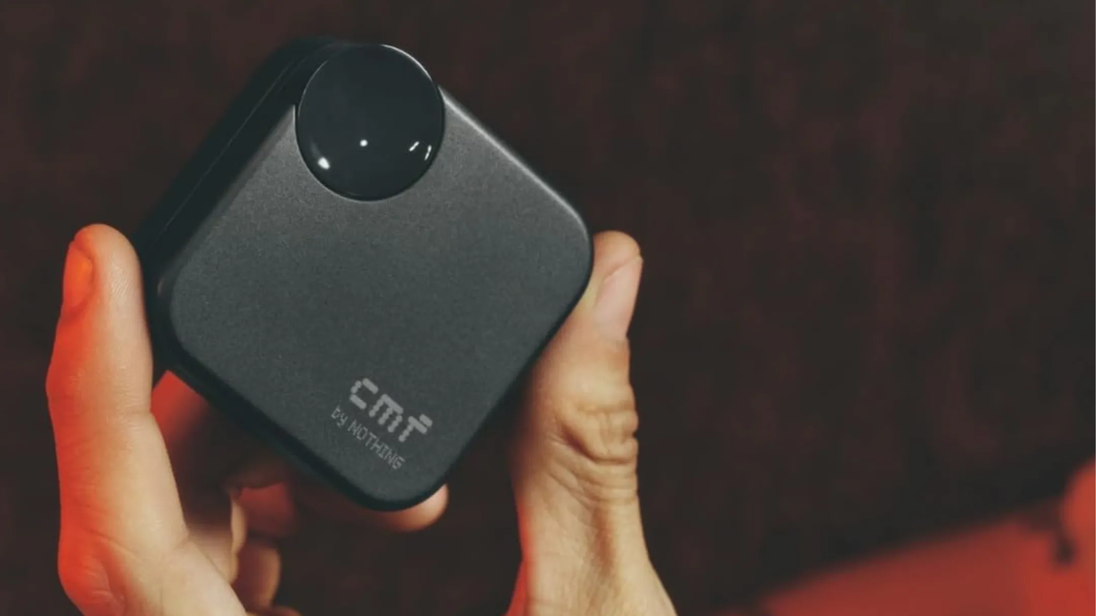 Một người đang cầm tai nghe không dây CMF Buds 2a màu đen, hộp sạc được mở, cho thấy thiết kế nhỏ gọn và tiện lợi
