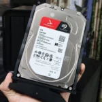 Người dùng đang cầm ổ cứng HDD, minh họa cho việc ổ cứng cũ làm chậm máy tính