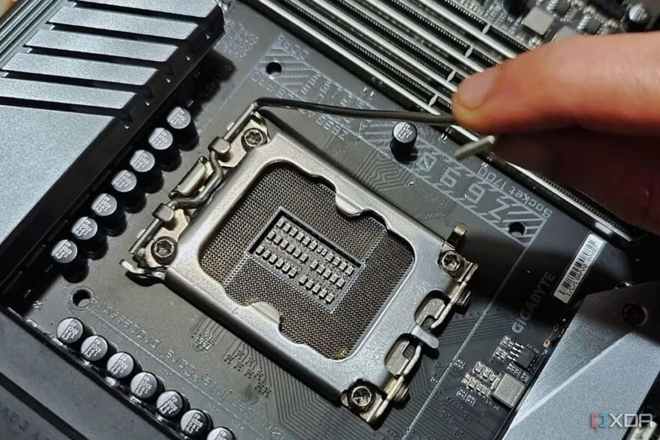 Người dùng đang kiểm tra cần gạt kim loại cạnh socket CPU trên bo mạch chủ