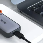 Ổ cứng SSD di động SSK nhỏ gọn đặt cạnh máy tính xách tay, thể hiện tính tương thích đa nền tảng và dễ dàng kết nối.