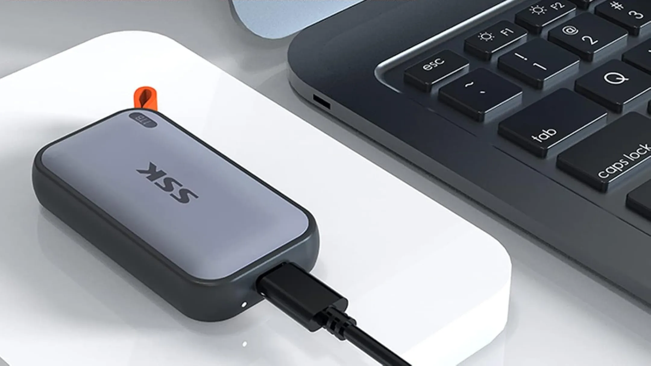 Ổ cứng SSD di động SSK nhỏ gọn đặt cạnh máy tính xách tay, thể hiện tính tương thích đa nền tảng và dễ dàng kết nối.