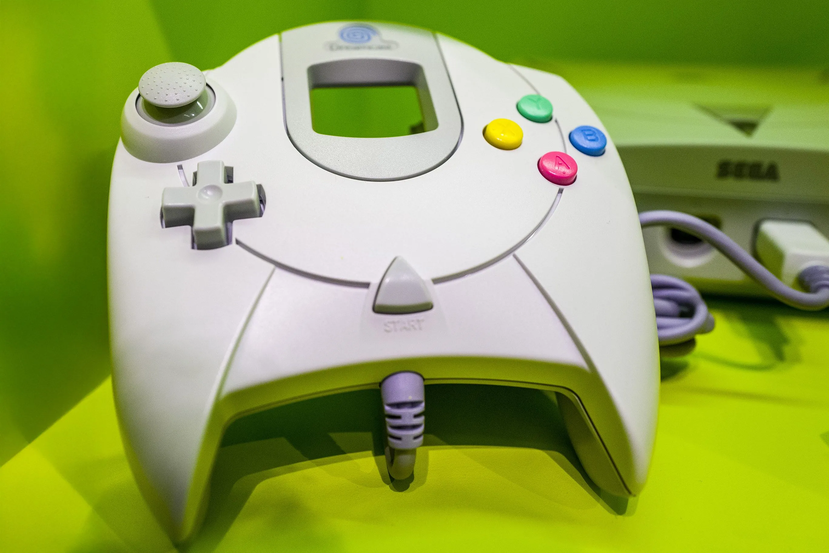 Tay cầm điều khiển Sega Dreamcast màu trắng với logo Dreamcast rõ nét, thể hiện thiết kế đặc trưng của console