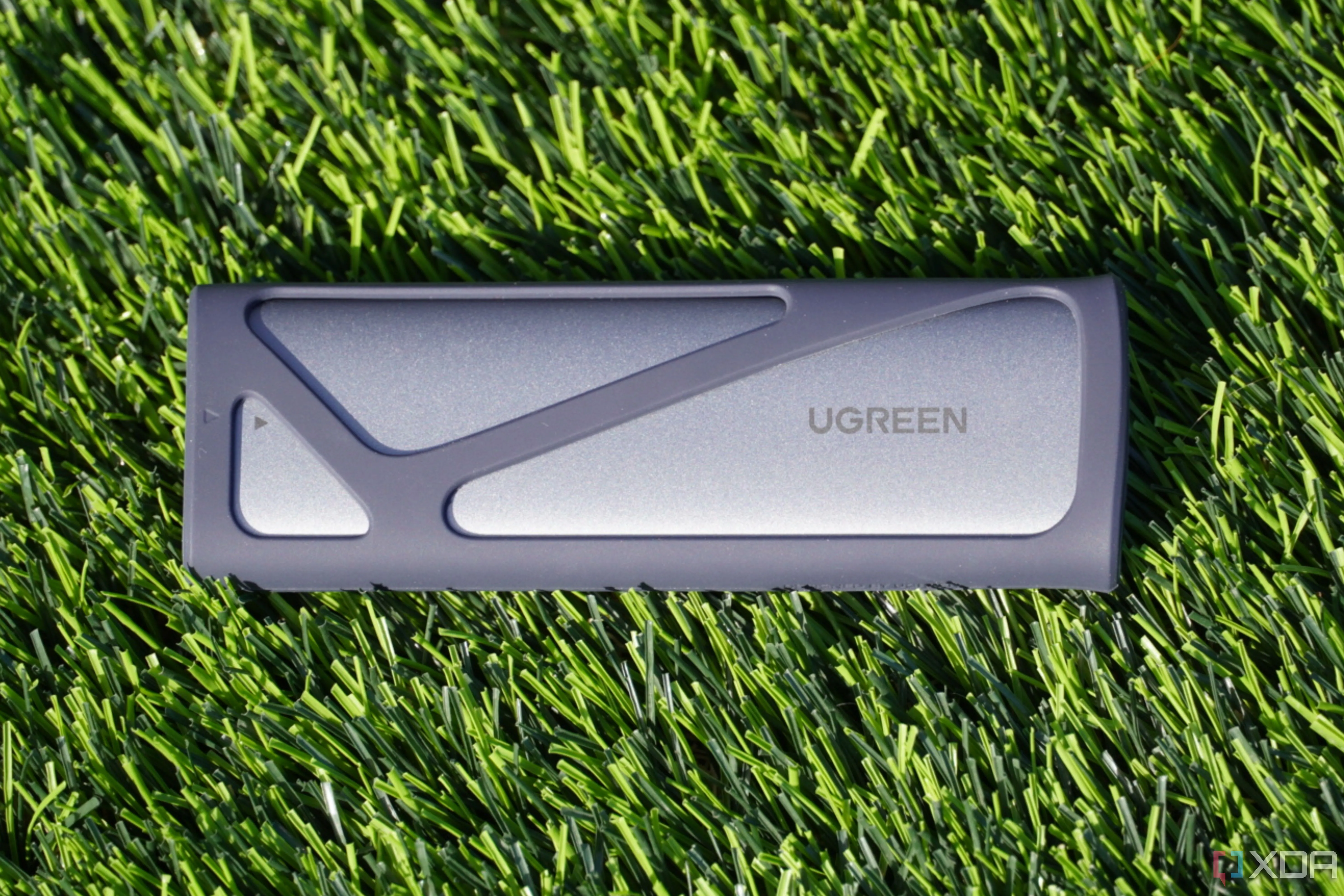Vỏ bọc SSD Ugreen được đặt trên nền cỏ xanh, thể hiện sự nhỏ gọn và tiện lợi